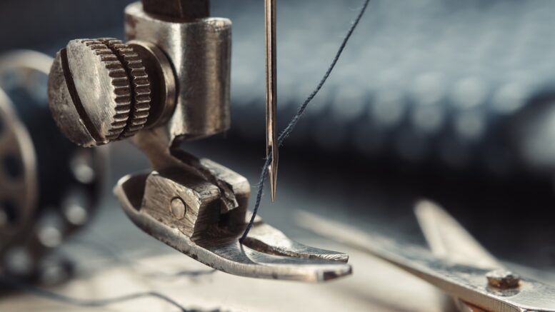 Close up of sewing needle. Tailoring scissors on working part of antique sewing machine.