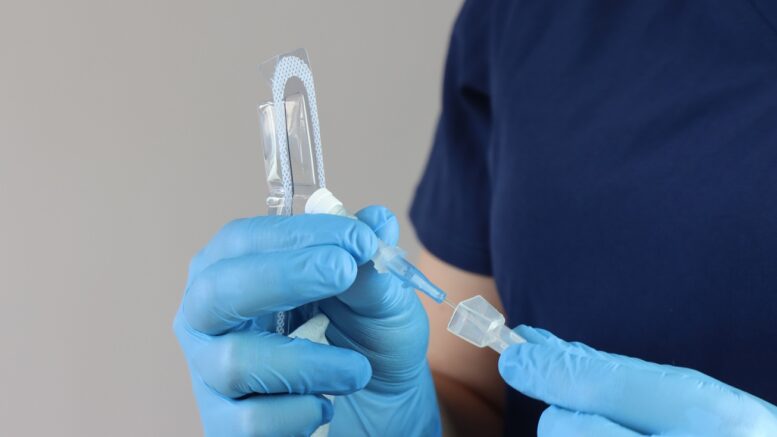 Health care professional wearing gloves manipulating the peripheral catheter pack