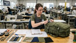 Quality-control specialist performing a first article inspection on a military tactical backpack.